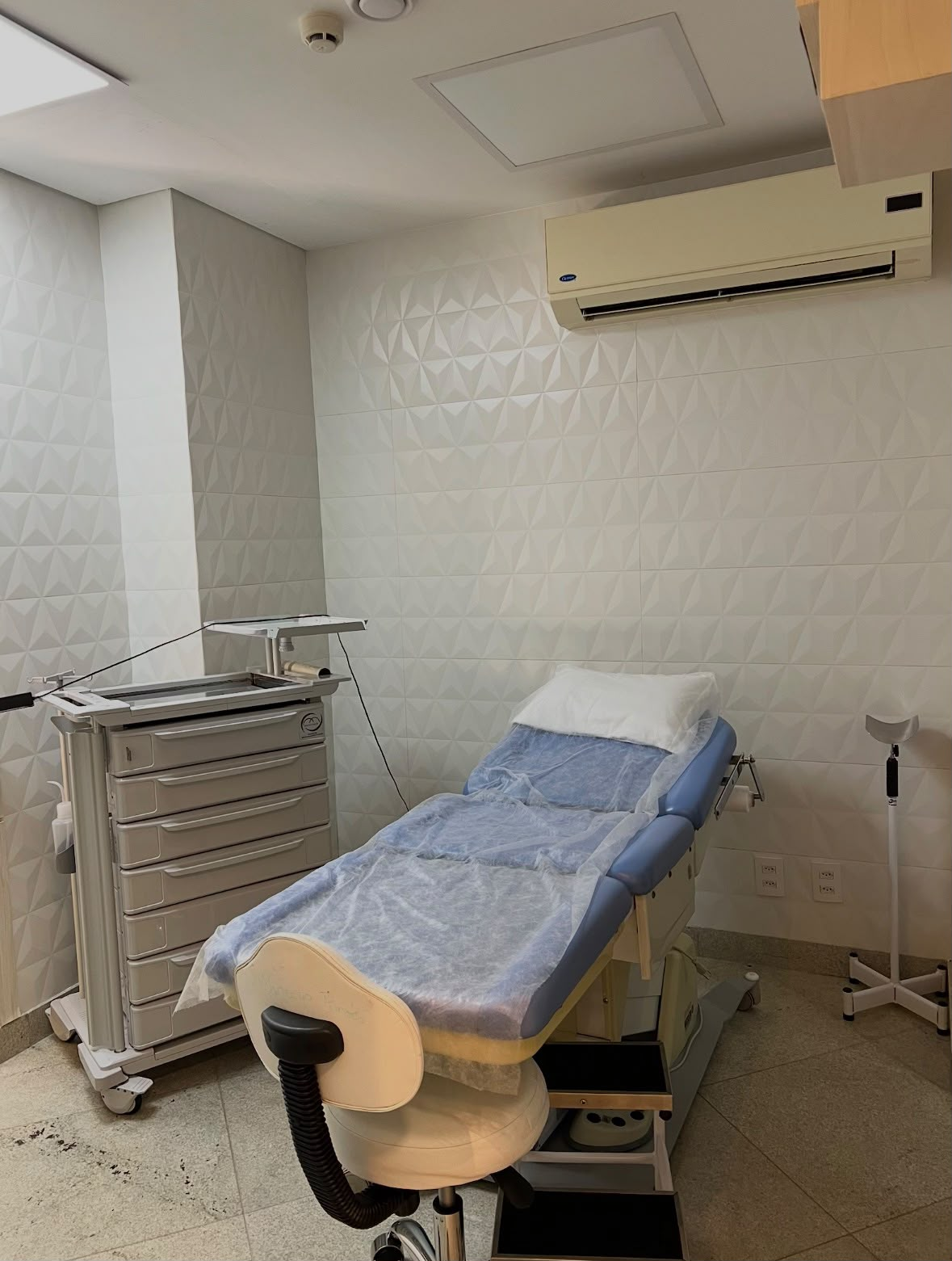 Sala de atendimento equipada com maca e mobiliário clínico.
